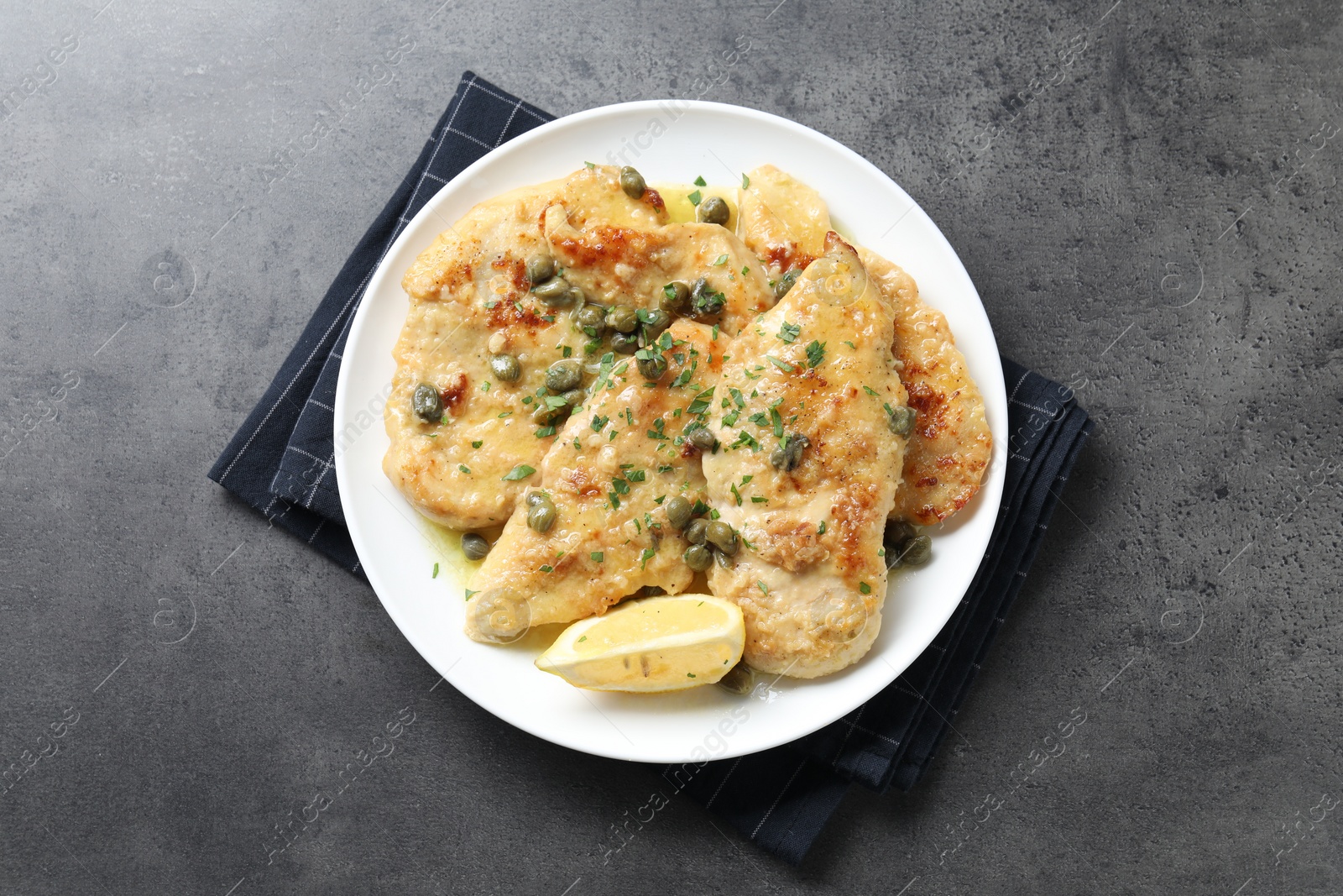 Photo of Delicious chicken piccata with herbs on grey table, top view