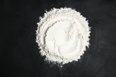 Photo of Pile of flour on black table, top view