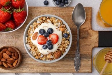 Photo of Tasty granola, yogurt and fresh berries served on light table, flat lay. Healthy breakfast