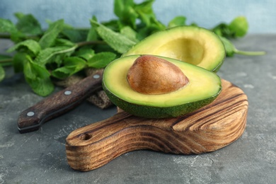 Photo of Wooden board with cut avocado on table