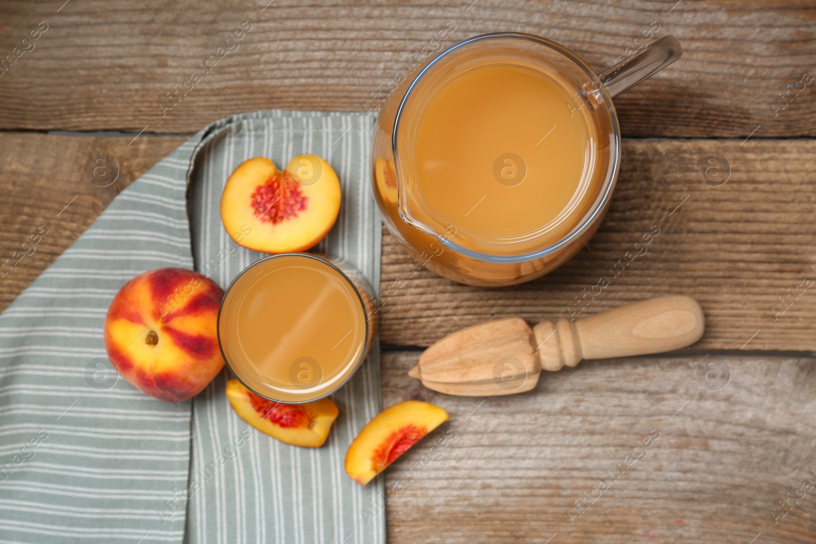 Photo of Delicious peach juice, fresh fruits and citrus reamer on wooden table, flat lay