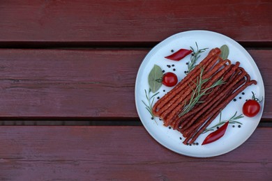 Photo of Tasty dry cured sausages (kabanosy) and ingredients on wooden table, top view. Space for text