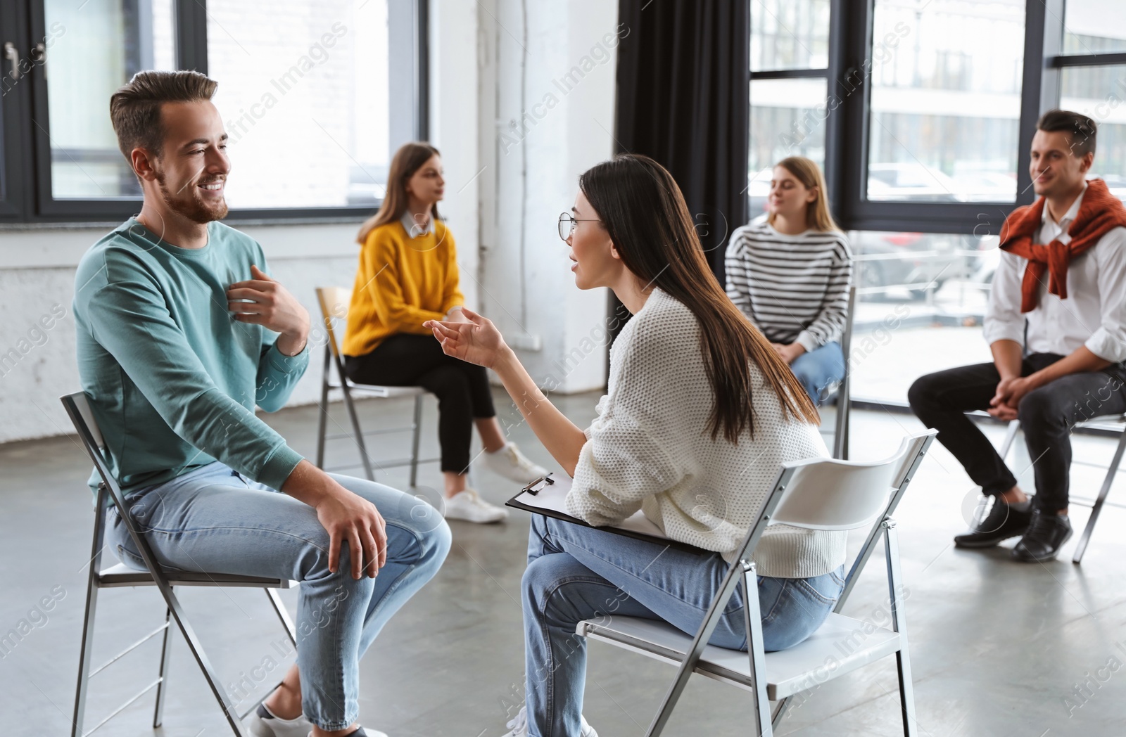 Photo of Psychotherapist working with patient in group therapy session indoors