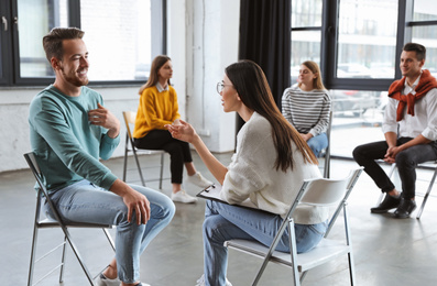 Photo of Psychotherapist working with patient in group therapy session indoors