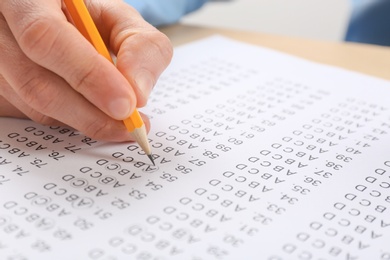 Student filling answer sheet at table, closeup