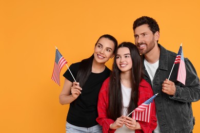 Photo of 4th of July - Independence Day of USA. Happy family with American flags on yellow background, space for text