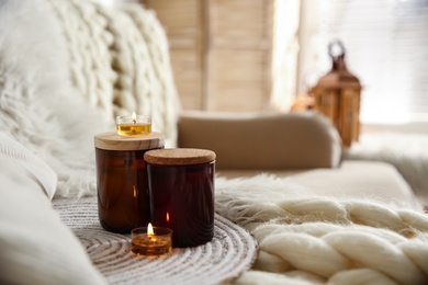 Photo of Candles on beige sofa with knitted blanket. Interior design