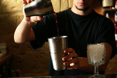 Bartender preparing fresh alcoholic cocktail at bar counter, closeup