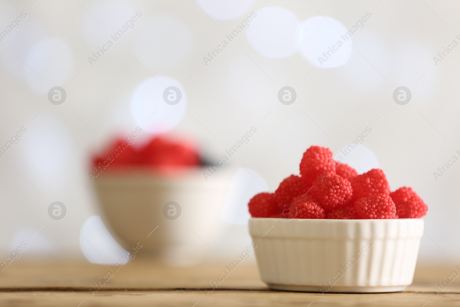 Photo of Delicious jelly candies on wooden table against blurred background, closeup. Space for text
