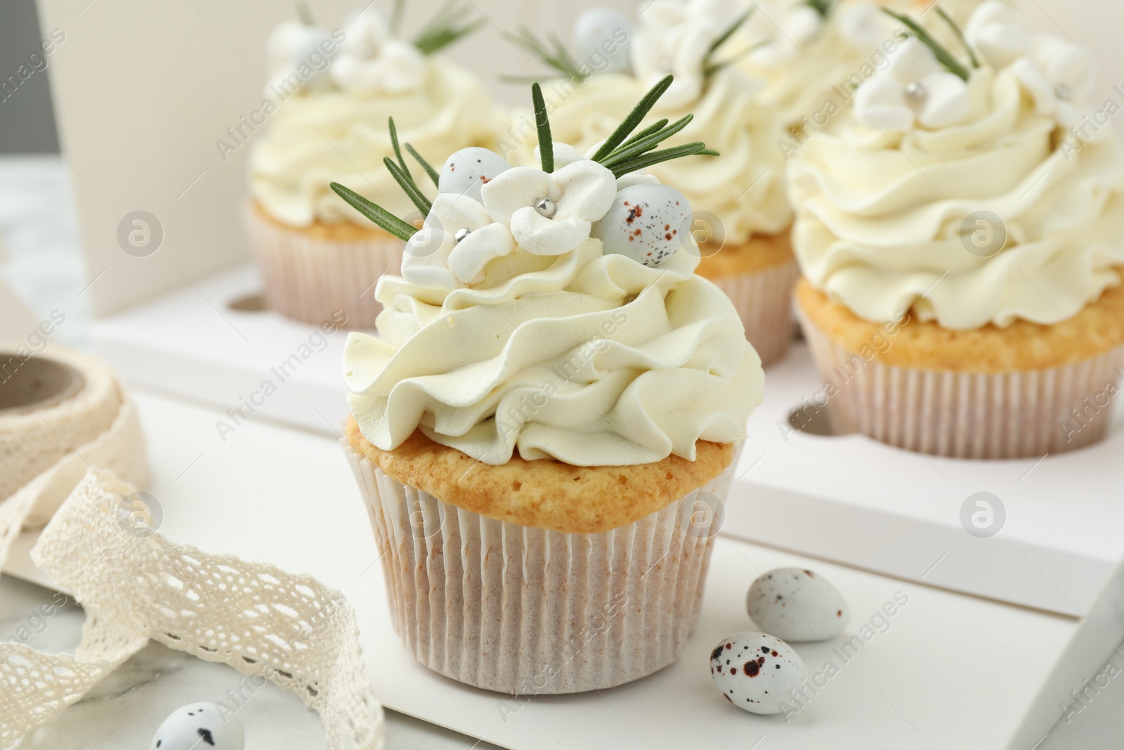 Photo of Tasty Easter cupcakes with vanilla cream on table, closeup