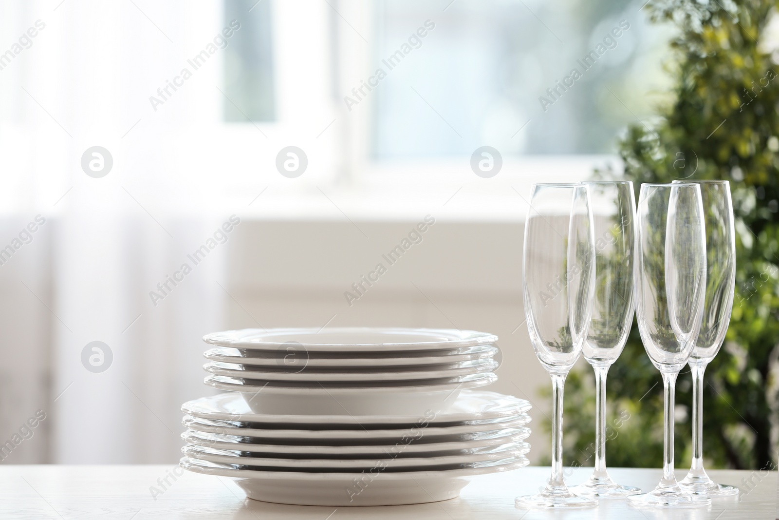 Photo of Set of clean dishware and champagne glasses on table indoors. Space for text