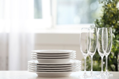 Photo of Set of clean dishware and champagne glasses on table indoors. Space for text