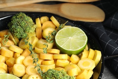Photo of Raw yellow carrot with lime and broccoli in frying pan, closeup