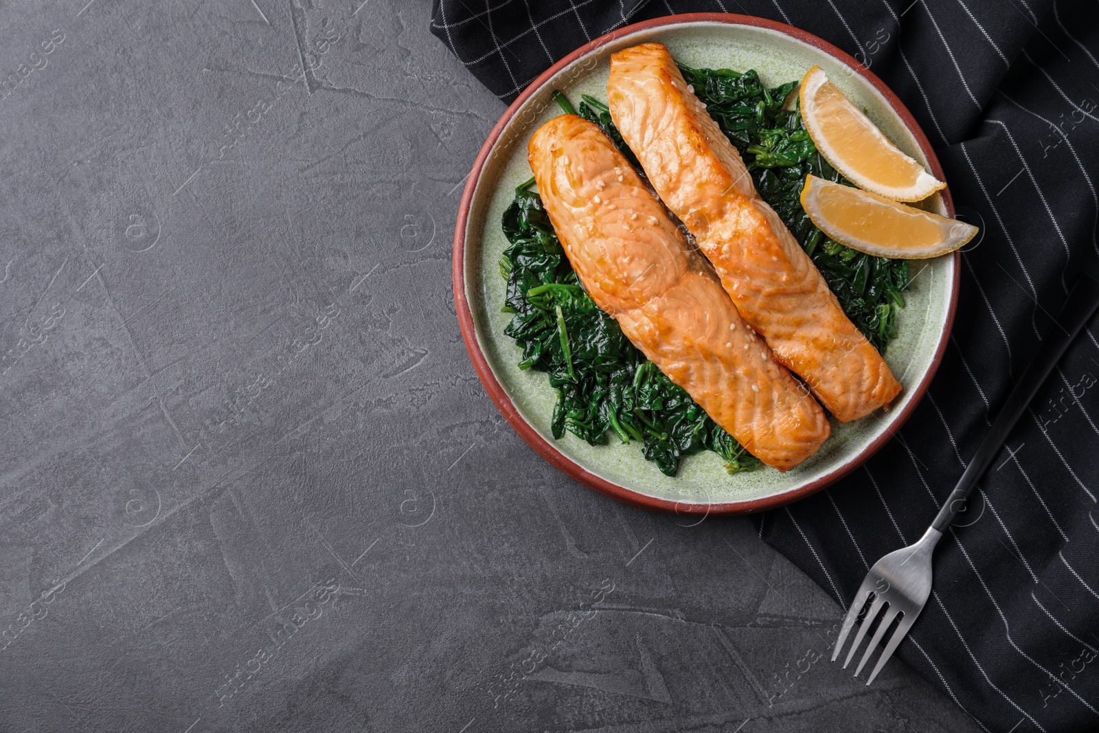 Photo of Tasty salmon with spinach and lemon on grey table, flat lay. Space for text