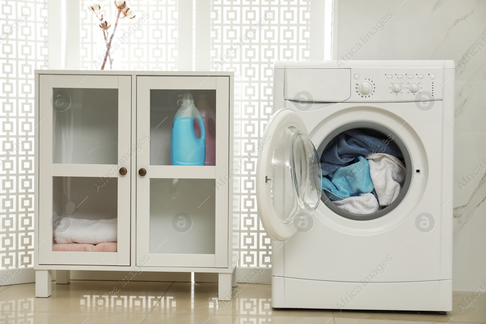 Photo of Modern washing machine with towels in bathroom