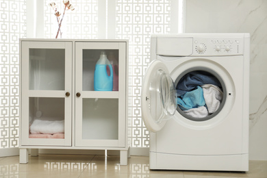 Modern washing machine with towels in bathroom