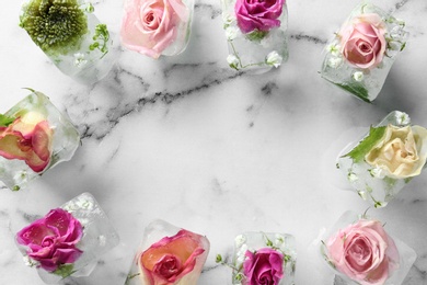 Photo of Frame made of ice cubes with flowers on marble background, flat lay. Space for text