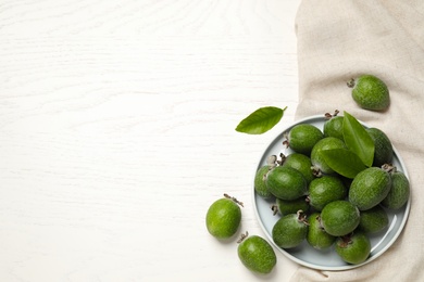 Flat lay composition with fresh green feijoa fruits on white wooden table, space for text