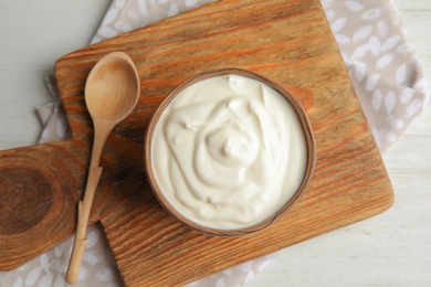 Photo of Wooden bowl with creamy yogurt served on table, top view