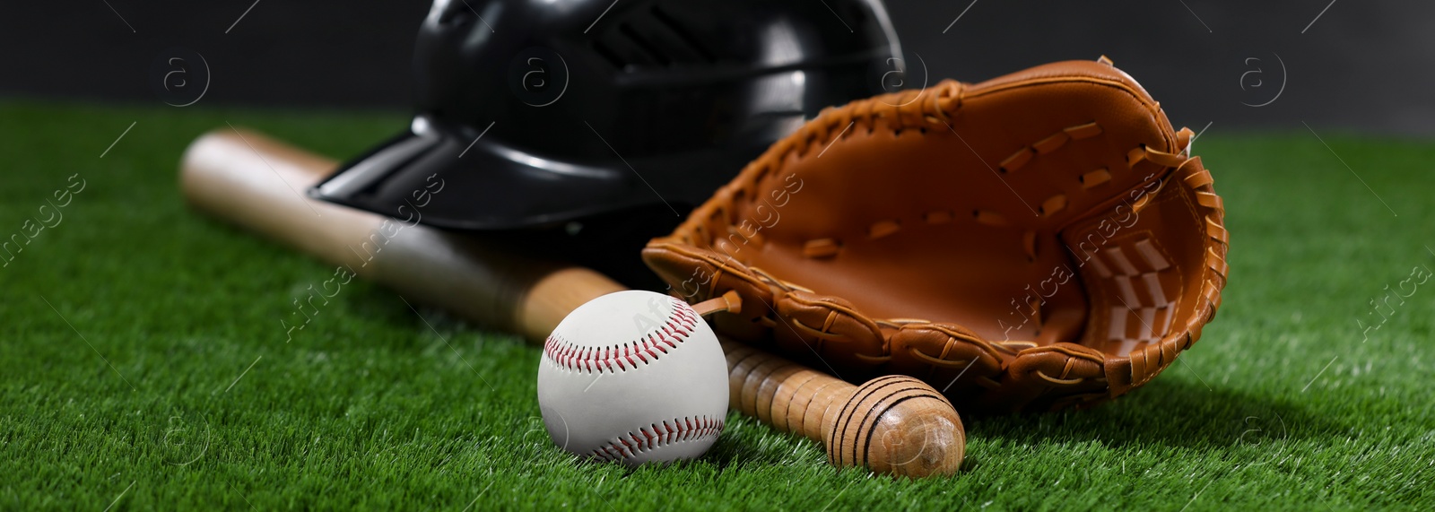 Image of Leather baseball glove, batting helmet, bat and ball on green grass, banner design