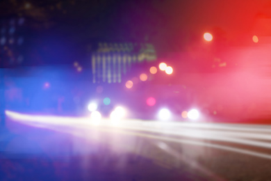 Image of Blurred view of police cars on street at night