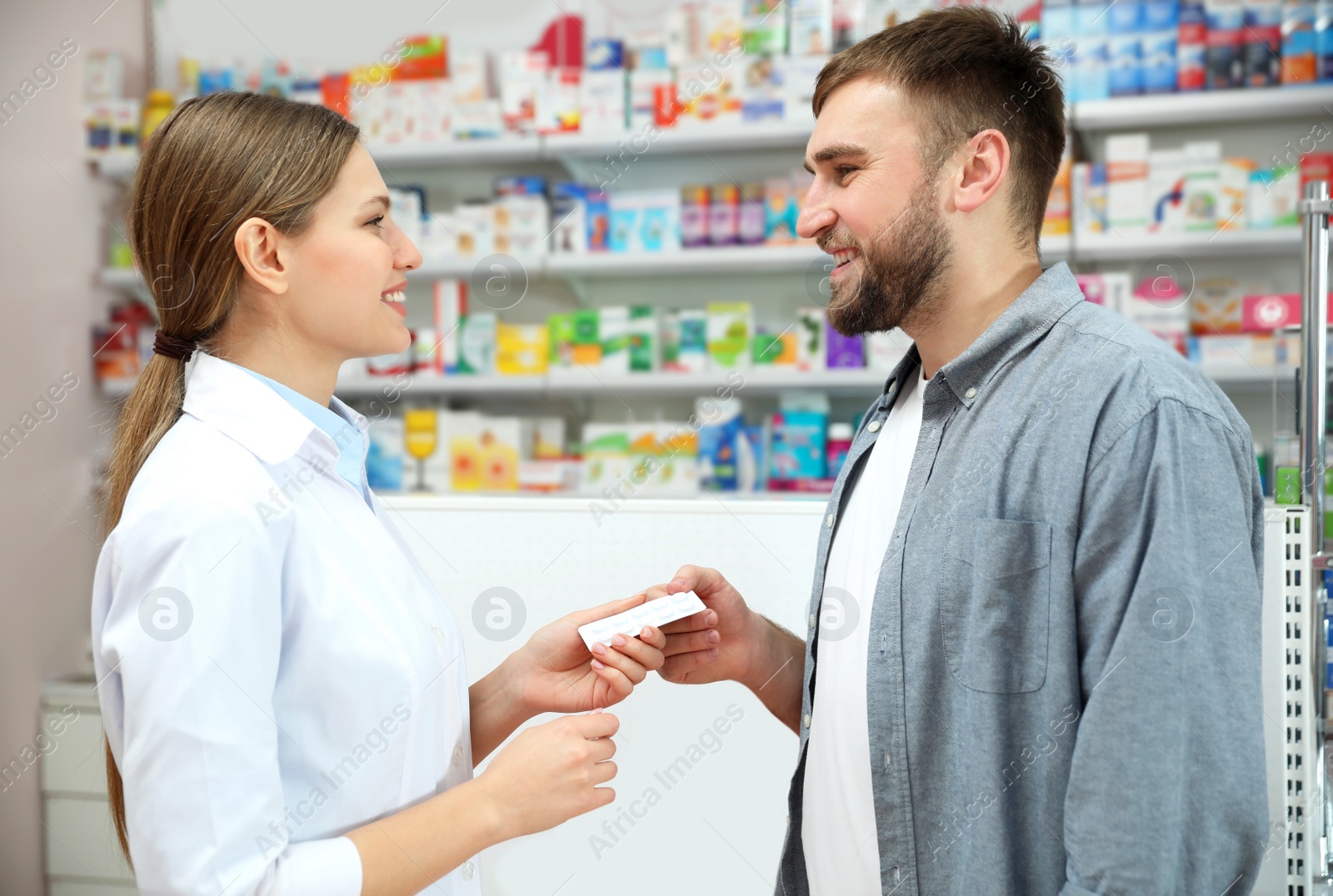 Image of Professional pharmacist giving pills to customer in modern drugstore