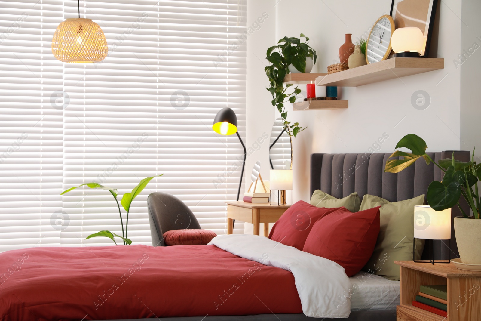 Photo of Stylish bedroom interior with comfortable bed, dressing table, lamps and green houseplants