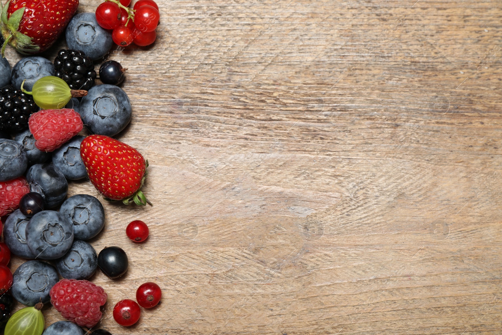 Photo of Different fresh berries on wooden table, flat lay. Space for text