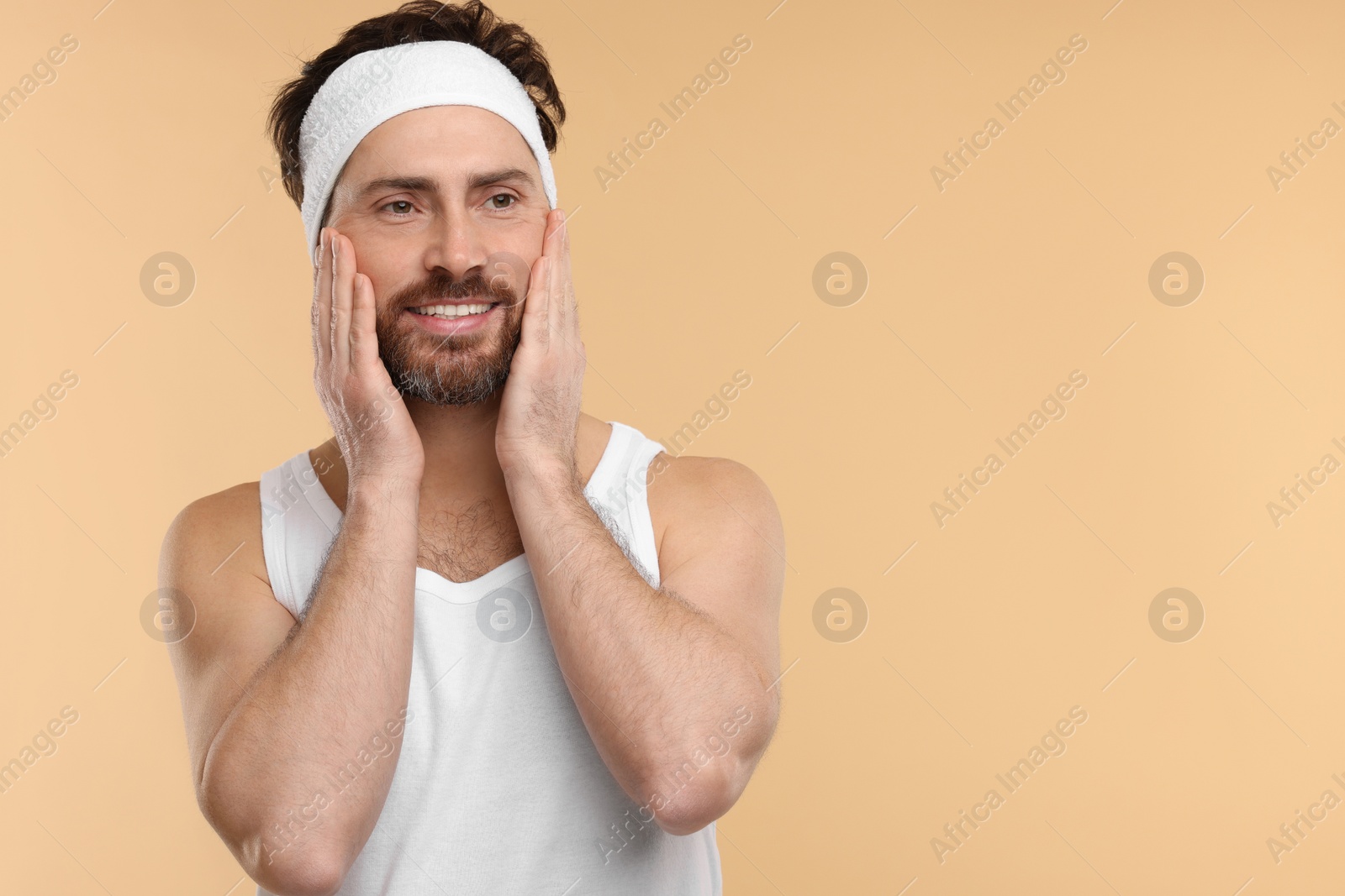 Photo of Washing face. Man with headband on beige background, space for text