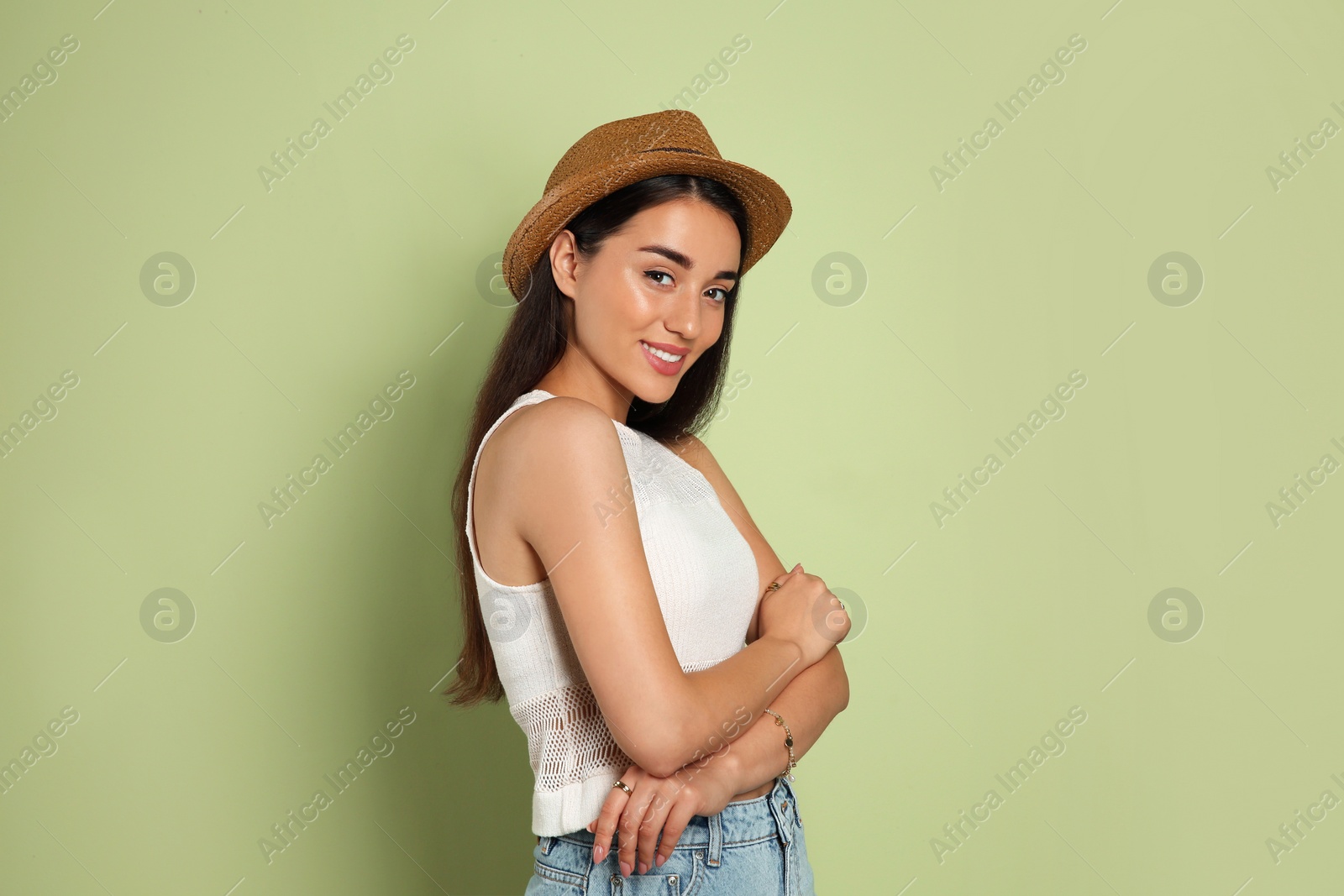 Photo of Beautiful young woman wearing straw hat on olive  background. Stylish headdress