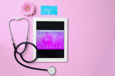 Photo of Tablet with word GYNECOLOGY, business card, flower and stethoscope on pink background, flat lay. Space for text