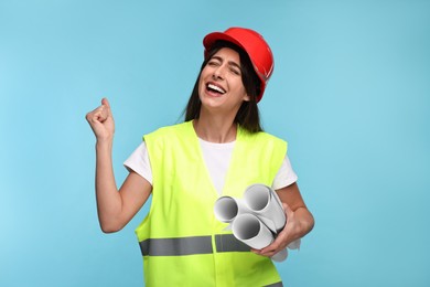 Photo of Architect in hard hat with drafts on light blue background