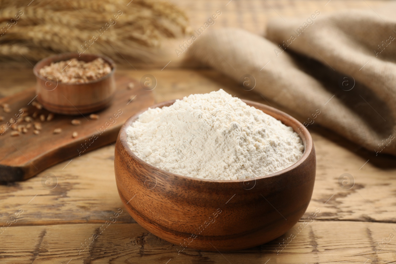 Photo of Wheat flour in bowl on wooden table