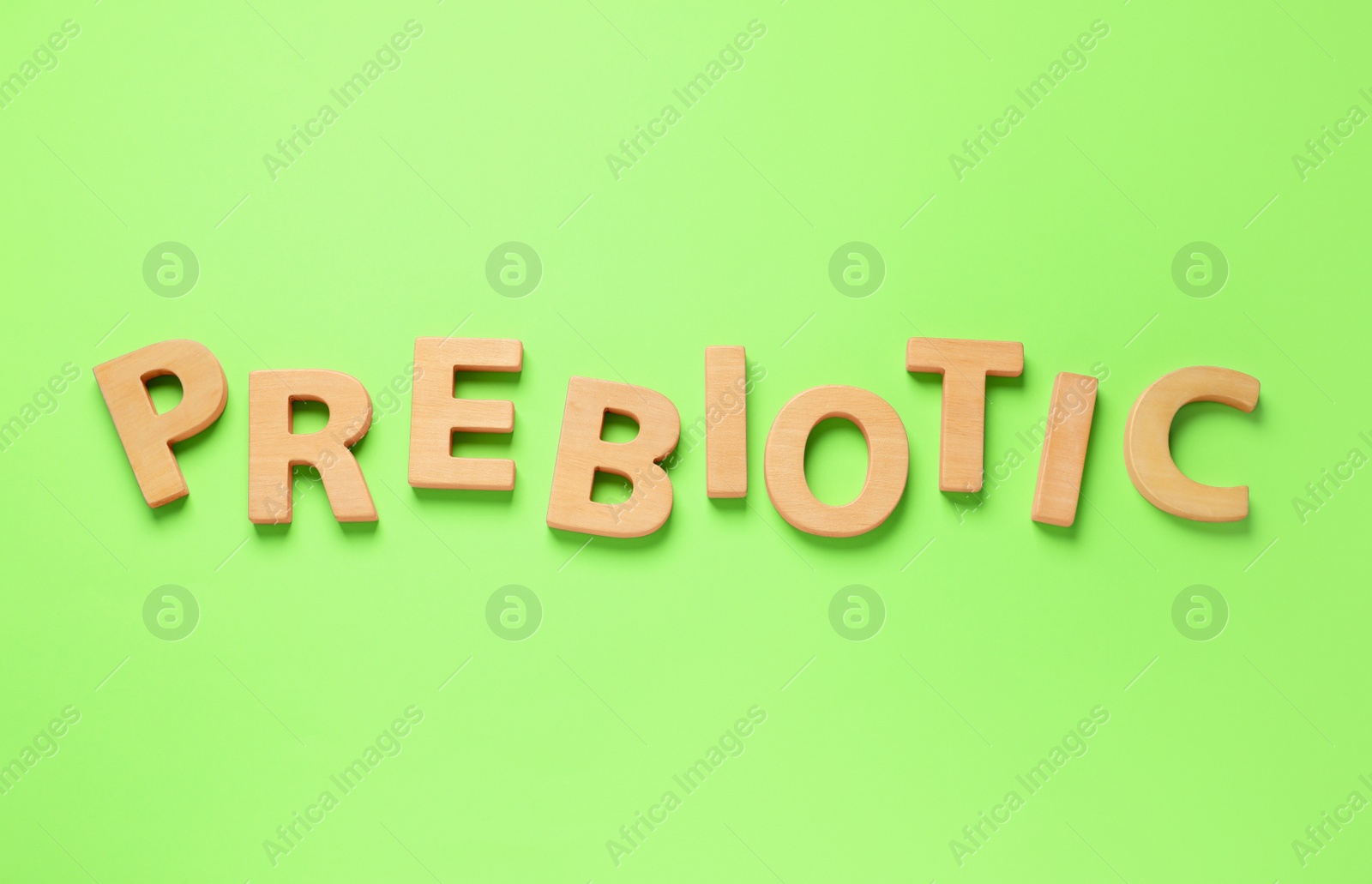 Photo of Word Prebiotic made of wooden letters on light green background, top view