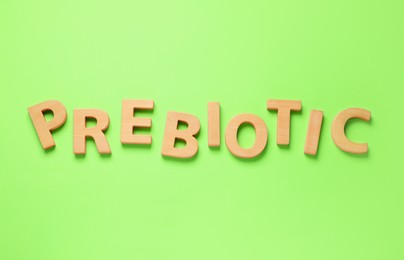 Word Prebiotic made of wooden letters on light green background, top view