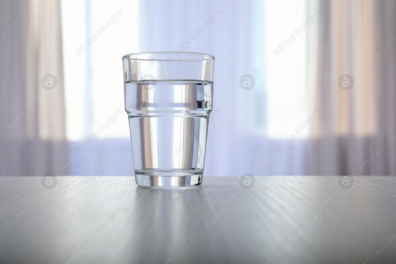 Photo of Glass of water on table against blurred background