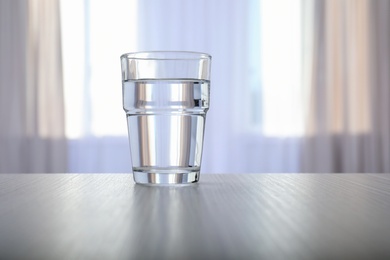 Glass of water on table against blurred background