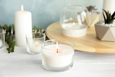 Photo of Burning aromatic candle and plants on table