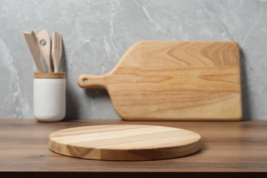 Photo of Wooden cutting boards and utensils on table near gray wall, closeup