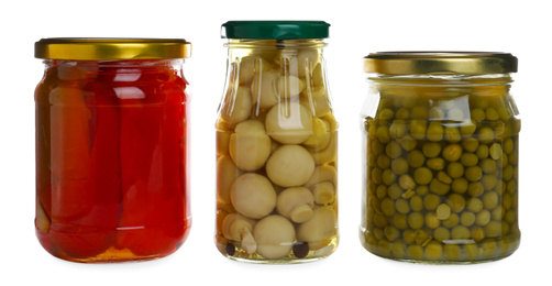 Photo of Glass jars of different pickled vegetables isolated on white