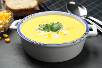 Photo of Delicious creamy corn soup served on black table