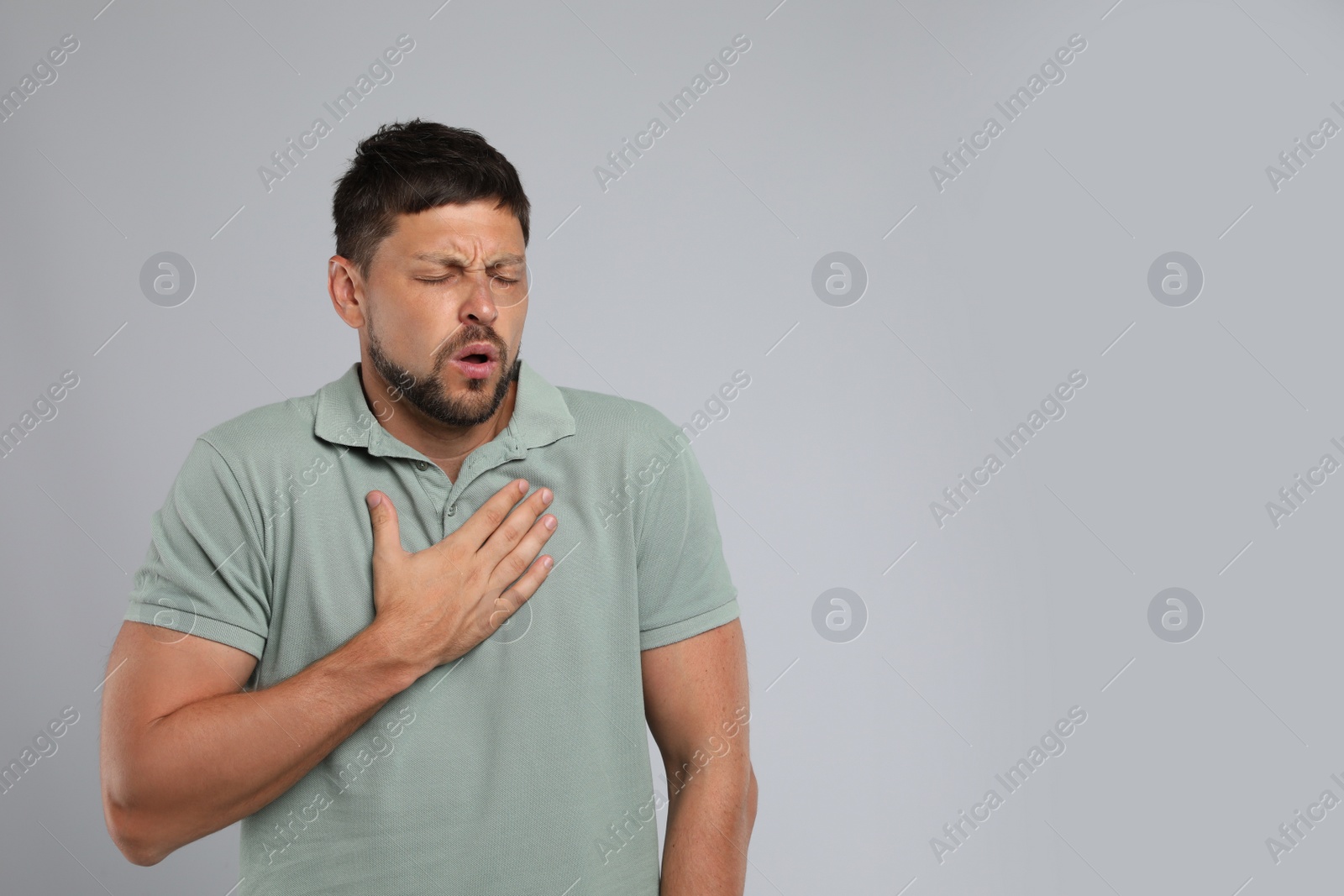 Photo of Man suffering from pain during breathing on grey background, space for text