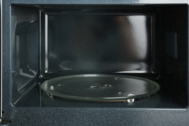 Photo of Open empty microwave oven, closeup. Inside view