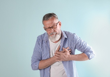 Photo of Mature man having heart attack on color background