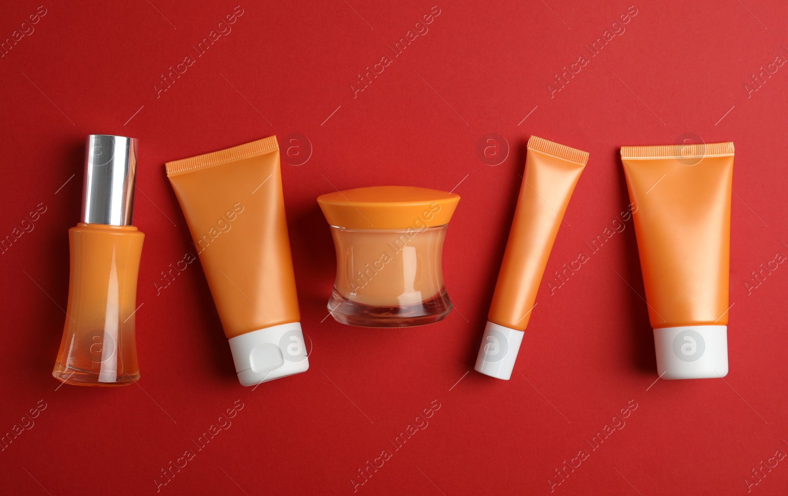 Photo of Set of luxury cosmetic products on red background, flat lay