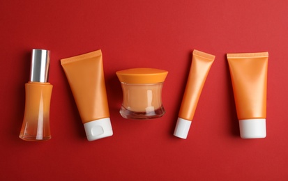 Photo of Set of luxury cosmetic products on red background, flat lay