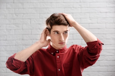 Portrait of young man with beautiful hair on brick wall background