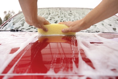 Photo of Man washing red car with sponge, closeup