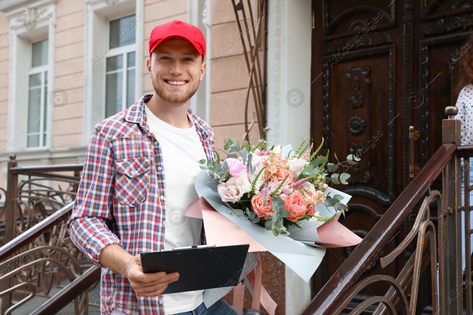 Photo of African-American woman receiving flower bouquet from delivery man at door
