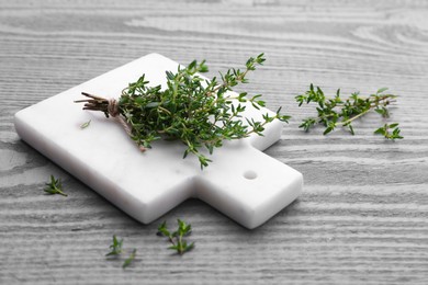 Photo of Board with aromatic fresh thyme on grey wooden table